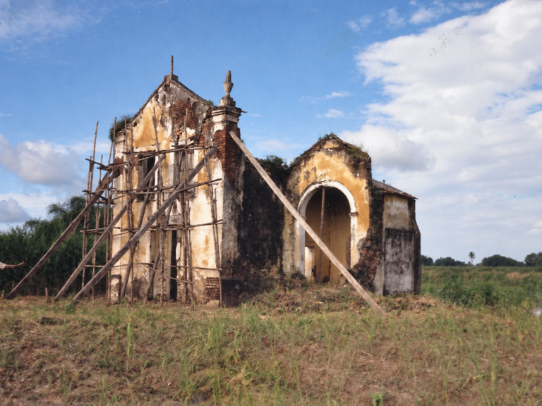 Versão editorial tratada de fotografia histórica: igreja em estado de conservação, com escoramentos e andaimes preservados.